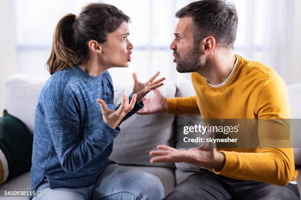 mid adult couple arguing on sofa at home. - estranged imagens e fotografias de stock