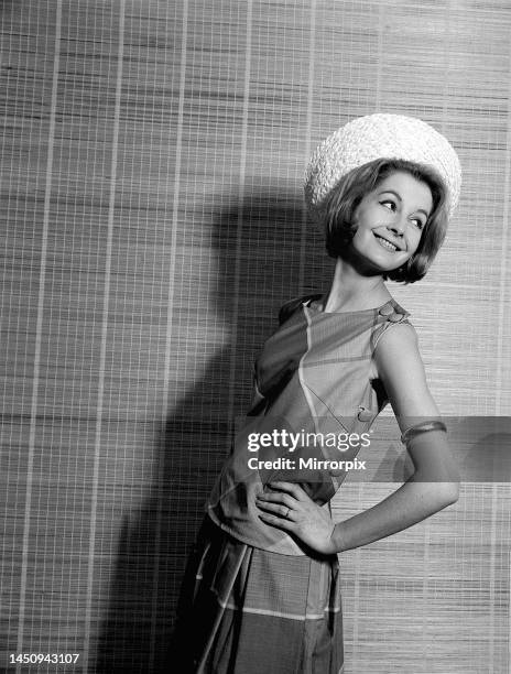 Sandra Paul standing with her hands on her hips, wearing a checked beach top dress and gold bangle on her arm. 26th April 1961.