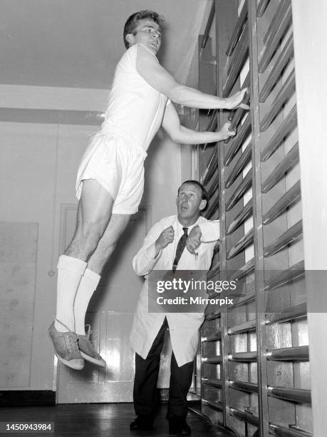 Arsenal physiotherapist Bertie Mee watches intently as Hendon outside right Terry Howard indulges in some gymnasium training, in an effort to get his...