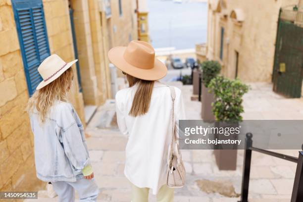 two females tourists walking on the stairs while exploring the old city - malta city stock pictures, royalty-free photos & images