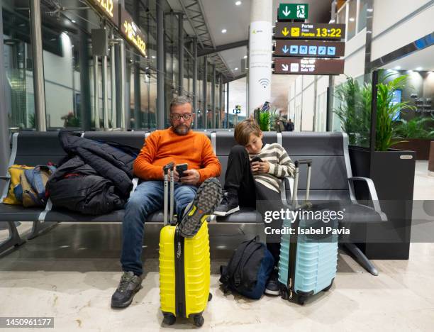 father and son waiting for flight at the airport lounge - family airport stock pictures, royalty-free photos & images