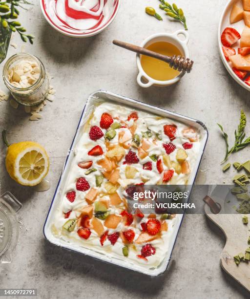 frozen yogurt bark with fruits and honey on kitchen table with ingredients - gefrorener joghurt stock-fotos und bilder
