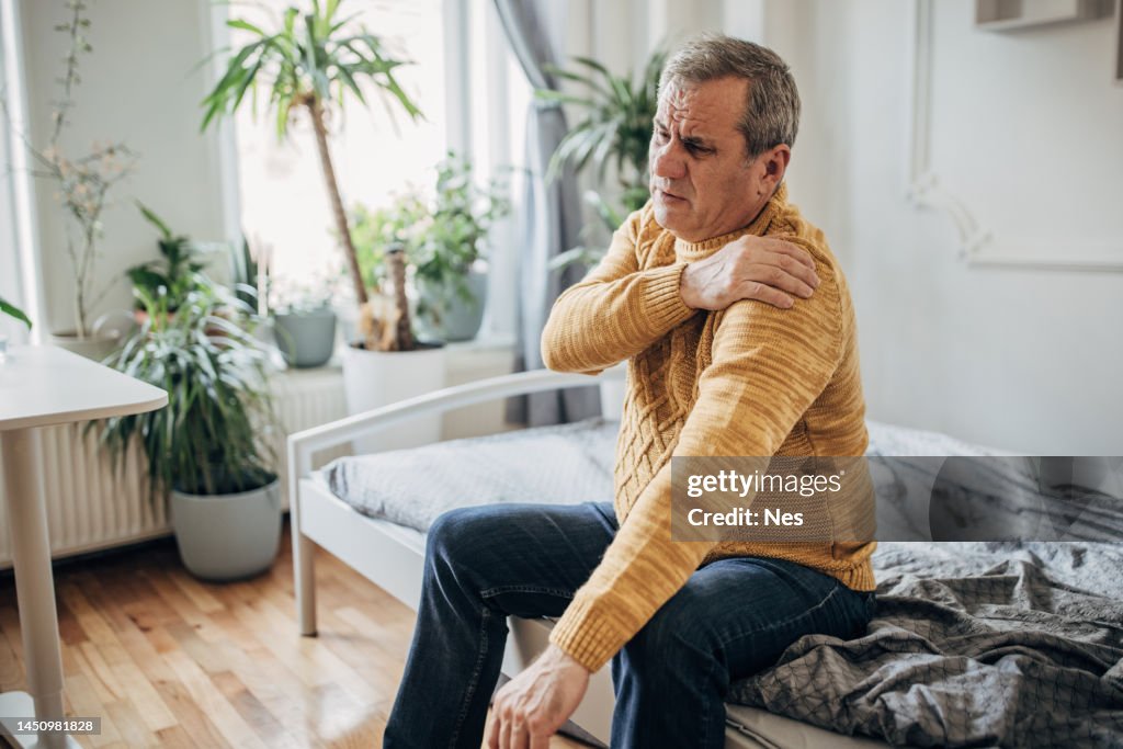 Un homme tient une main sur une épaule malade