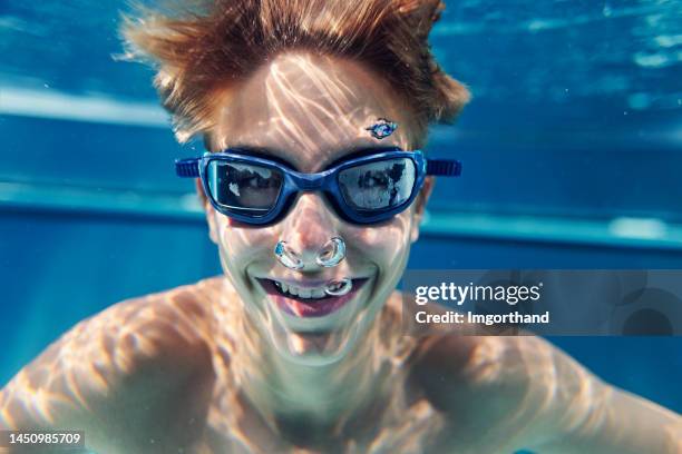 porträt eines teenagers, der unter wasser im schwimmbad schwimmt - child bubble stock-fotos und bilder