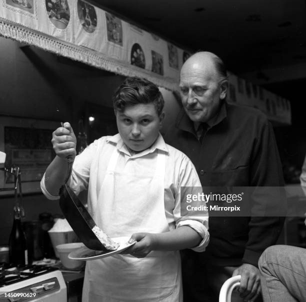 Johnny Cradock with pupil cook John Harper in Fanny Cradock's kitchen. John is turning out an omelette. 28th October 1962.