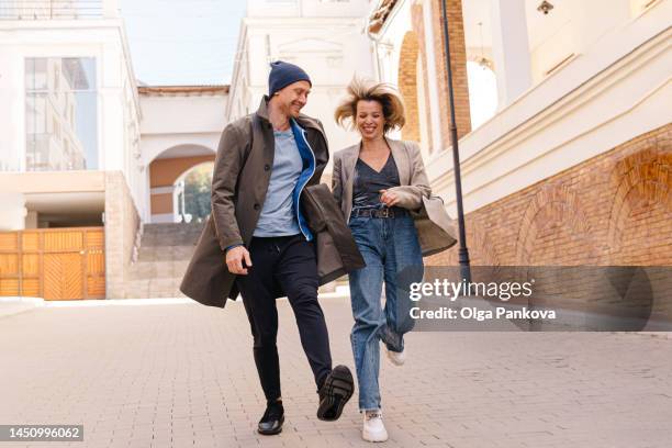 mid age couple having fun and running down the street - woman walks down street stock pictures, royalty-free photos & images