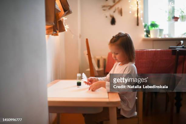 girl child at children's table makes experiment with paper christmas tree and green solution of salt. - child with advent calendar stock pictures, royalty-free photos & images
