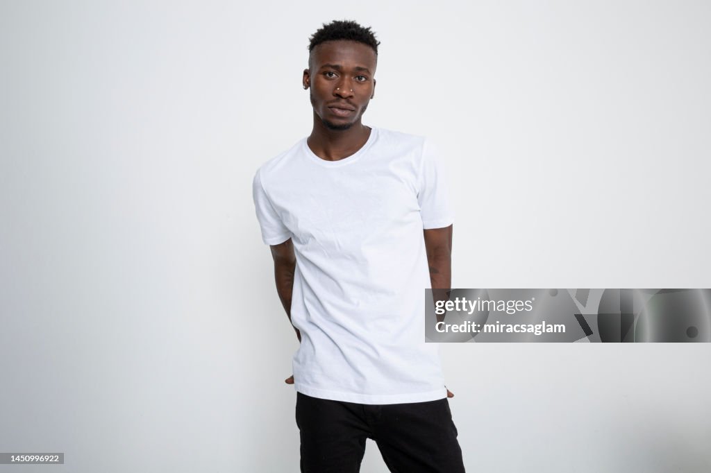 African-American man in white t-shirt looking at camera against white background.