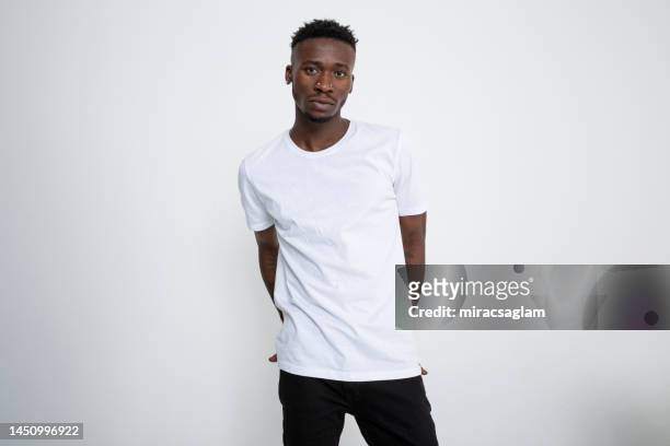 african-american man in white t-shirt looking at camera against white background. - blank t shirt model stock pictures, royalty-free photos & images
