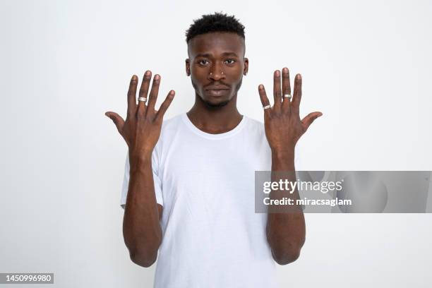 african-american man wearing white t-shirt showing his hands against white background and looking at camera. - african man white background stock pictures, royalty-free photos & images