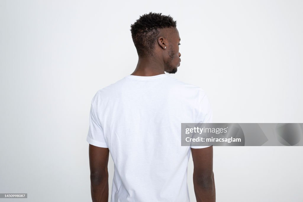 Hombre afroamericano con camiseta blanca sobre fondo blanco.