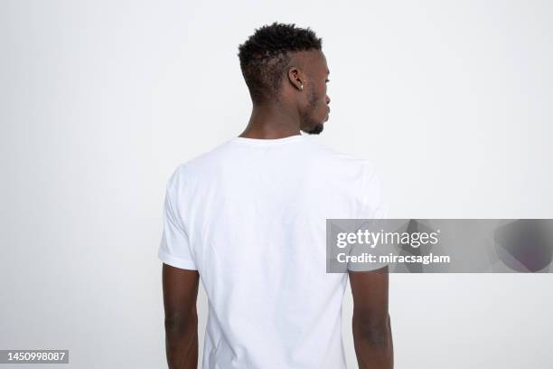 african-american man in white t-shirt against white background. - model tshirt stockfoto's en -beelden