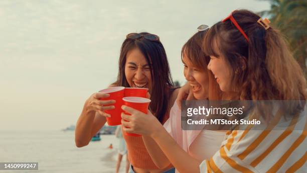 group of young asian women celebrating and drinking alcohol on tropical beach. - asian female friends drinking soda outdoor stock pictures, royalty-free photos & images