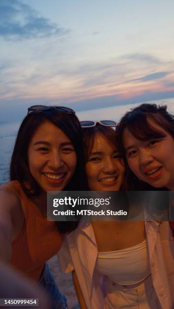 熱帯のビーチで電話で写真を撮るアジアの若い女性のグループ。休日の休暇のコンセプト。 - group selfie ストックフォトと画像