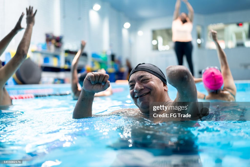 Portrait of a senior man with left arm amputation during a group fitness class at swimming pool