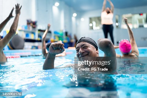 Portrait of a senior man with left arm amputation during a group fitness class at swimming pool Portrait of a senior man with left arm amputation during a group fitness class at swimming pool