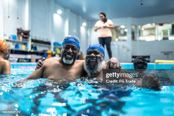 portrait of senior men hugging at swimming pool - vrijetijdsfaciliteiten stockfoto's en -beelden