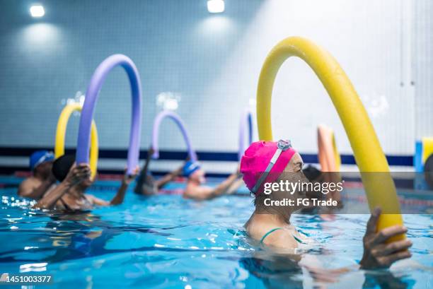 senior people exercising with noodle float at swimming pool - hydrotherapy stock pictures, royalty-free photos & images