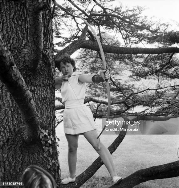 Bisham Abbey Physical recreation centre. A woman in one of the trees on the lawns in front of the Abbey get in a little archery practice. June 1952.