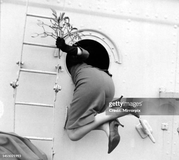 Beverley Janner holding mistletoe is pulled through a porthole by her sailor husband for a homecoming kiss as the crew of HMS Bulworth return for...