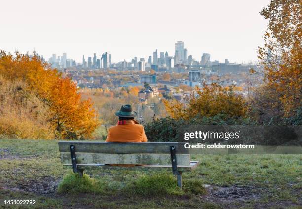 hombre mayor sentado en el banco del parque mirando el horizonte de la ciudad de londres desde hampstead heath - hampstead heath fotografías e imágenes de stock