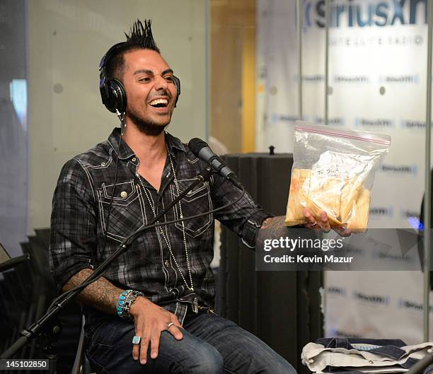 SiriusXM host Jose Mangin gives Slash tamales on SiriusXM's Octane in the SiriusXM Studio on May 23, 2012 in New York City.