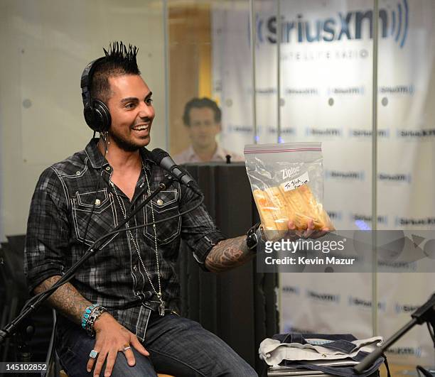 SiriusXM host Jose Mangin gives Slash tamales on SiriusXM's Octane in the SiriusXM Studio on May 23, 2012 in New York City.