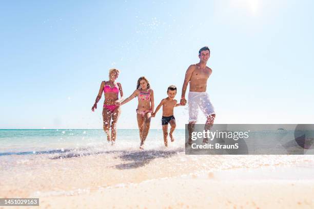 carefree family holding hands and running through sea. - egypt beach stock pictures, royalty-free photos & images