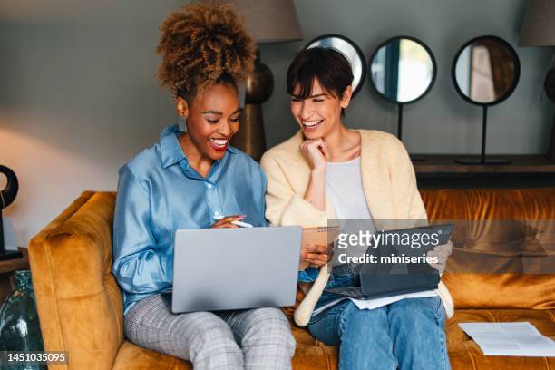 two happy colleagues working together in a home decor store - yellow sofa stock pictures, royalty-free photos & images