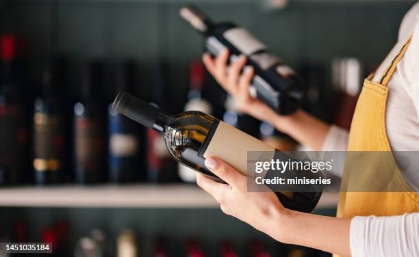 photo rapprochée de mains de femme tenant deux bouteilles de vin - bouteille de vin photos et images de collection