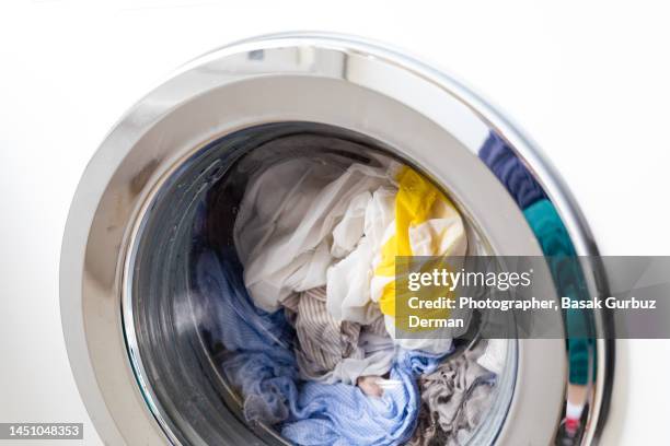 close-up on a white washing machine with light colored clothes in it - piumone foto e immagini stock