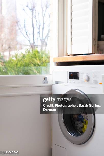 view of a laundry room with washing machine and a window - wasserglas stockfoto's en -beelden