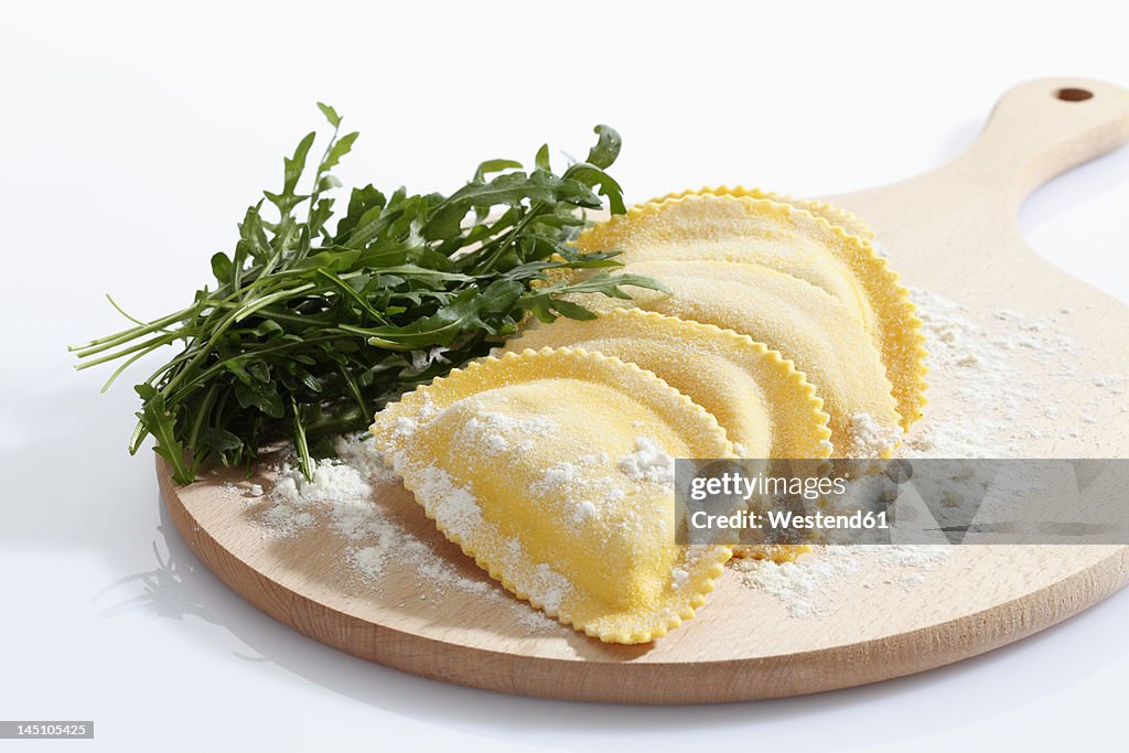 Crescent shape pasta with flour and rocket on chopping board