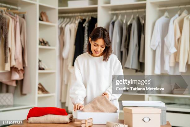 female cleaning and arranging clothes in the closet - armadio a muro foto e immagini stock