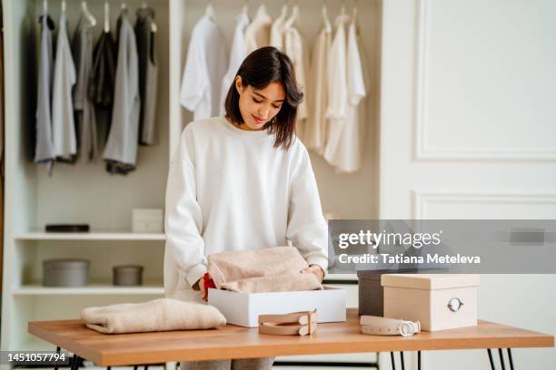 sales occupation. calm woman packing clothing in the boxes on the table in showroom or clothes store - shoes closet ストックフォトと画像