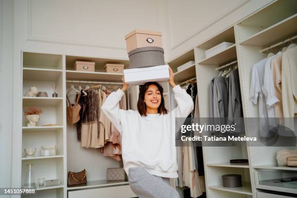 new clothes purchase. smiling woman carrying clothes boxes on her head near walk in wardrobe - wardrobe stock-fotos und bilder