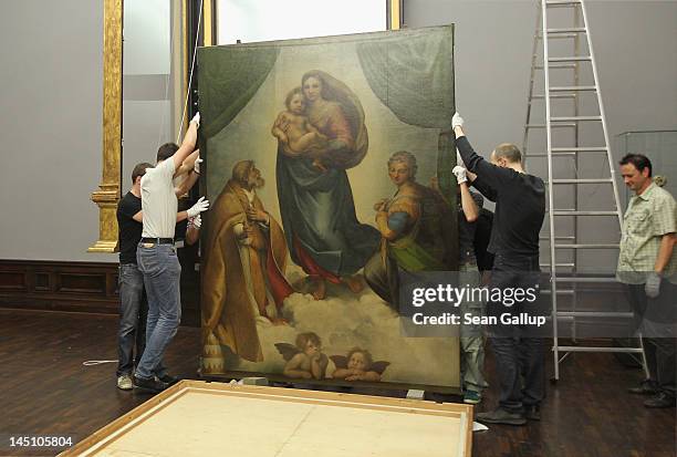 Gallery assistants lift the „Sistine Madonna” painting by 16th century Italian painter Raphael to hang it in its new frame at the Galerie Alte...