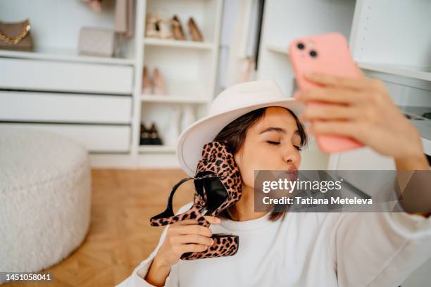 close up positive woman in hat taking selfie and sending aerial kiss while posing with leopard shoe as a phone near her ear - shoes closet ストックフォトと画像