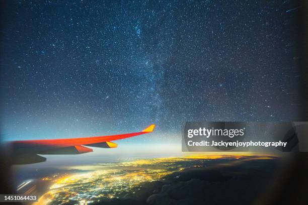 stunning milky way and city light with plane wing up on the sky - plane wing stock-fotos und bilder