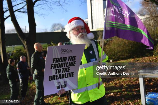 Demonstrator wearing a Santa hat holds a placard on a picket line at Manchester Ambulance Station on December 21, 2022 in Manchester, England....