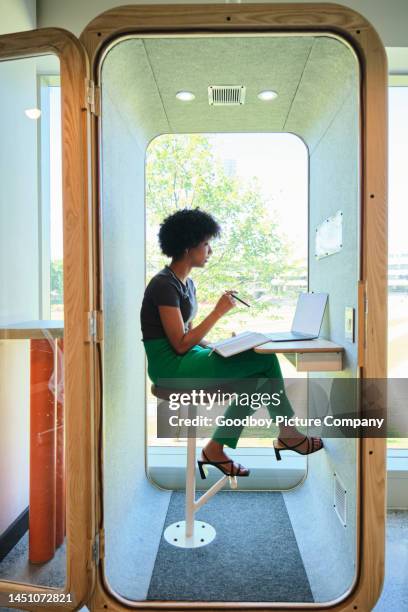 young businesswoman talking on a video call in an office pod - soundproof stock pictures, royalty-free photos & images