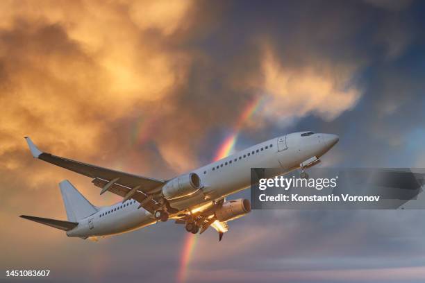 plane flies over scenic sunset cloud and double rainbow - plane landing stock-fotos und bilder