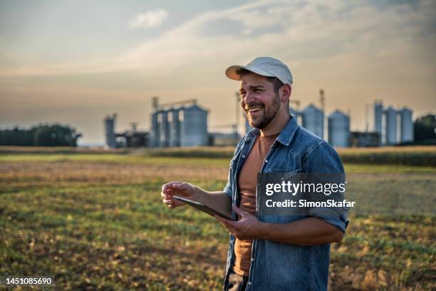 happy male farmer using digital tablet in field against sky - keps bildbanksfoton och bilder