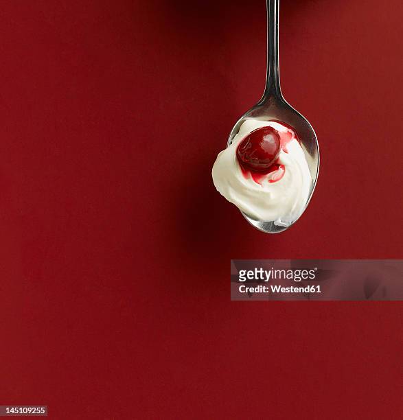 yogurt and cherry in spoon on red background - spion stock pictures, royalty-free photos & images