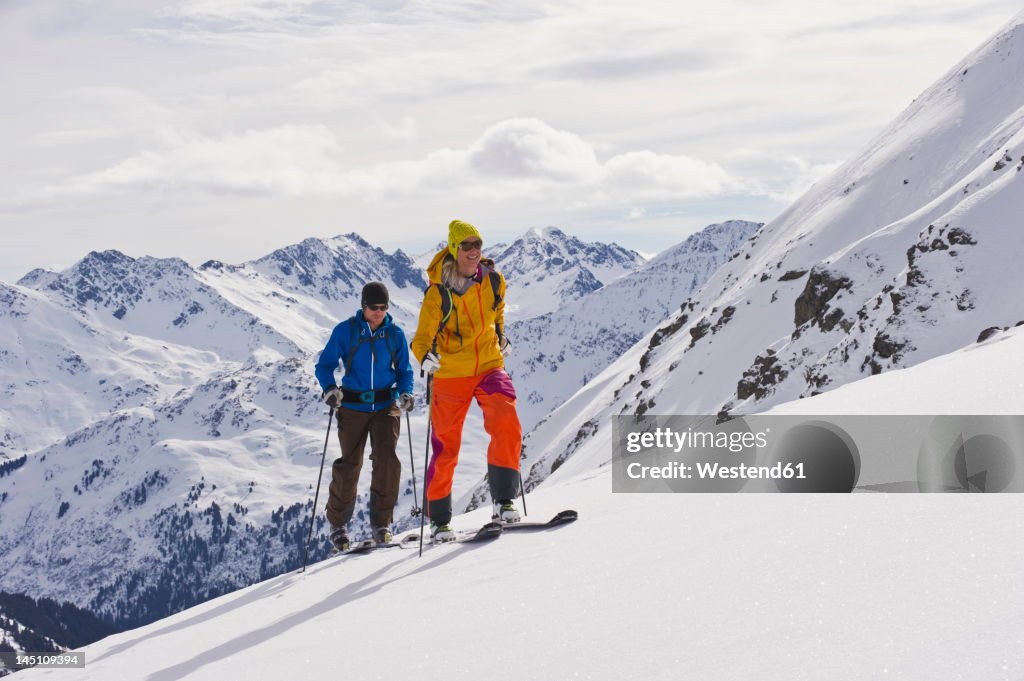 Austria, Stuben, Young couple doing telemark skiing on arlberg mountain