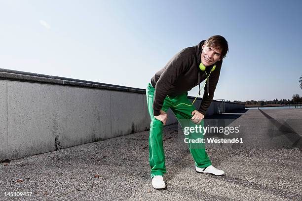 germany, bavaria, munich, young man resting after exercising - hand on knee fotografías e imágenes de stock