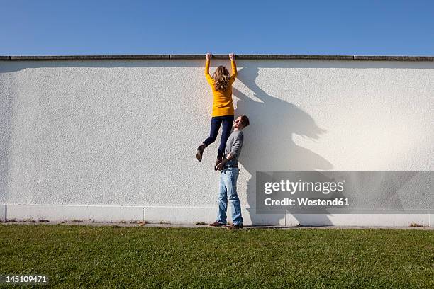 germany, bavaria, munich, young couple climbing wall - hilfe stock-fotos und bilder