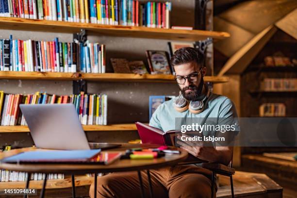 giovane studente maschio che studia in biblioteca - leggere foto e immagini stock