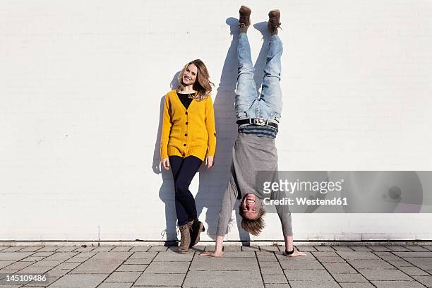 germany, bavaria, munich, young couple against wall, smiling - balancieren mauer stock-fotos und bilder