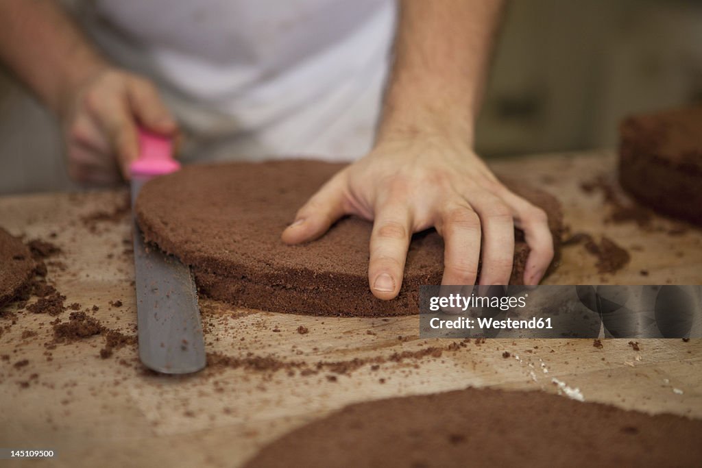 Germany, Bavaria, Munich, Baker cutting cake layers